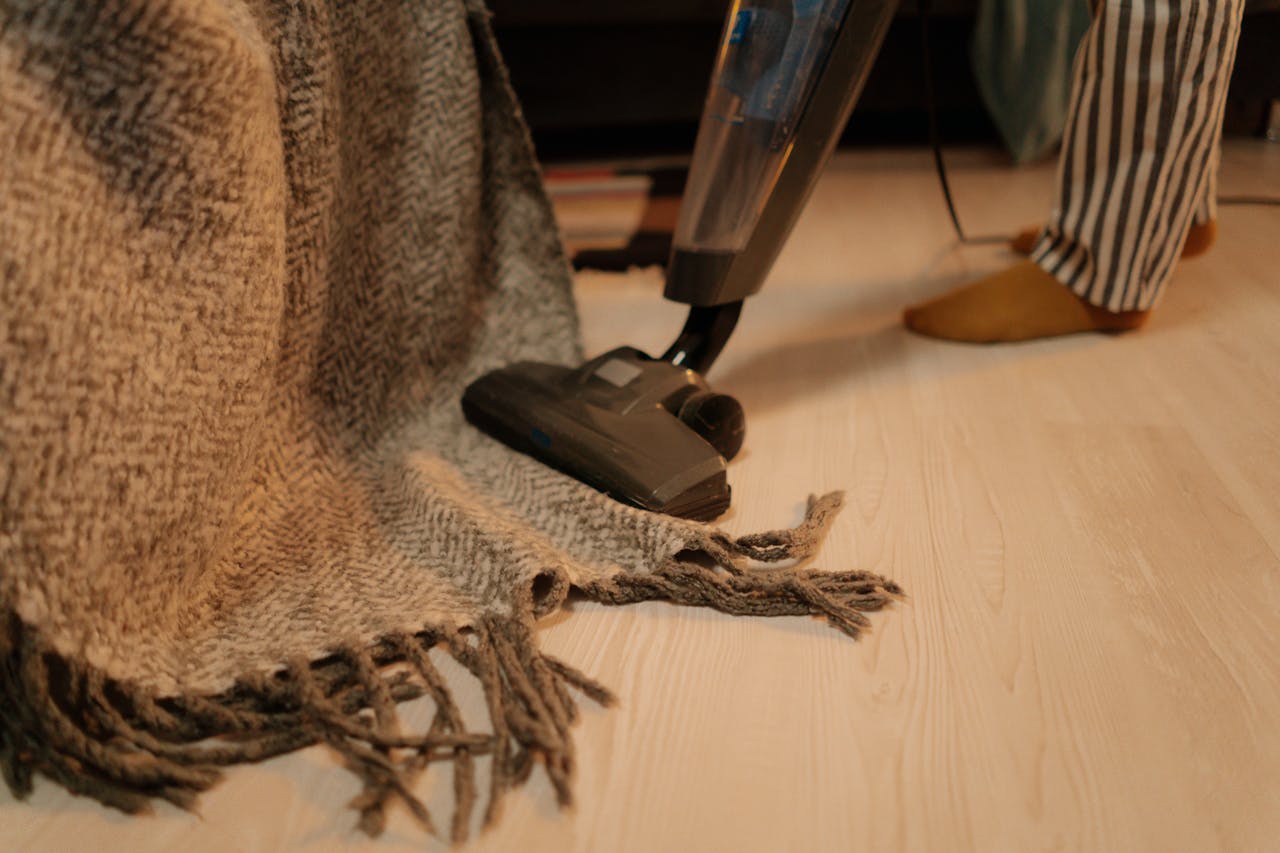 portfolio-03 Close-up of vacuum cleaner cleaning a woolen blanket on the floor indoors.